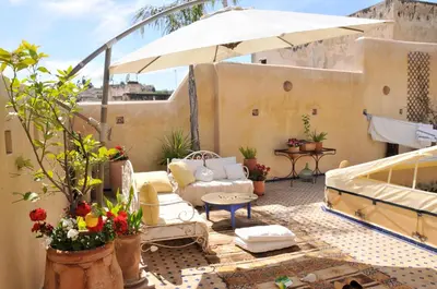a patio with an umbrella and chairs and a table at La Cheminée Bleue Fes in Fès