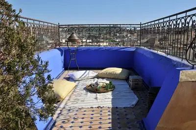 a blue balcony with pillows and a table on it at La Cheminée Bleue Fes in Fès