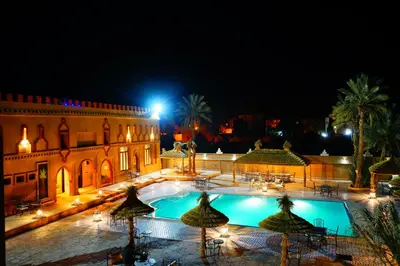 a building with a swimming pool at night at Kasbah Hotel Ziz Palace Rissani in Rissani