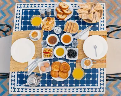 a breakfast table with breakfast foods on a blue and white table cloth at Kasbah Hotel Ziz Palace Rissani in Rissani