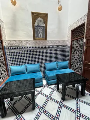 a living room with a blue couch and two tables at Dar atlas in Fès