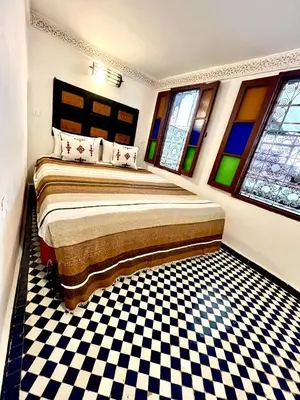 a bedroom with a bed and a checkered floor at Dar atlas in Fès