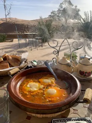 a bowl of soup with eggs in it on a table at Kasbah Erg Chebbi in Merzouga