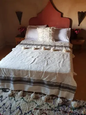 a bedroom with a bed with white sheets and pillows at Kasbah Erg Chebbi in Merzouga