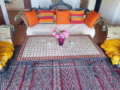a table with a vase of flowers on a bed at Kasbah Erg Chebbi in Merzouga