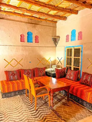 a living room with a wooden table and a couch at Kasbah Erg Chebbi in Merzouga