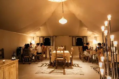 a room with people sitting at tables in a tent at Aiour Luxury Camp in Merzouga
