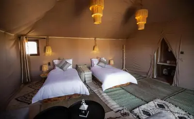 a bedroom with two beds in a tent at Aiour Luxury Camp in Merzouga