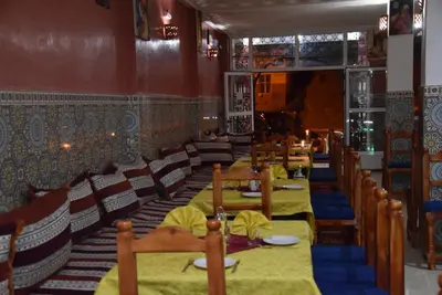 a dining room with tables and chairs in a restaurant at Hôtel Restaurant Dar Al Madina in Tinerhir