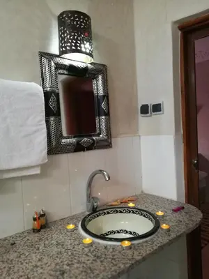 a bathroom counter with a sink and a mirror at Hôtel Restaurant Dar Al Madina in Tinerhir
