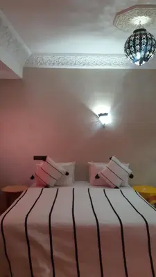a bedroom with a bed with pink and white pillows at Hôtel Restaurant Dar Al Madina in Tinerhir