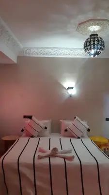 a bedroom with a bed with a person laying on it at Hôtel Restaurant Dar Al Madina in Tinerhir