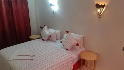 a bedroom with a bed with white sheets and pillows at Hôtel Restaurant Dar Al Madina in Tinerhir