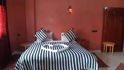 a bedroom with a bed with black and white stripes at Hôtel Restaurant Dar Al Madina in Tinerhir