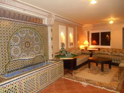 a living room with a couch and a tile wall at Tigmi Dar Samy in Bine el Ouidane