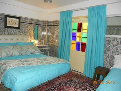 a bedroom with a bed and a colorful window at Tigmi Dar Samy in Bine el Ouidane