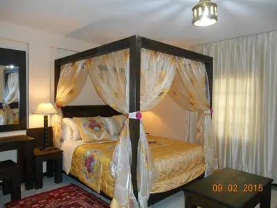 a bedroom with a canopy bed with curtains and a table at Tigmi Dar Samy in Bine el Ouidane