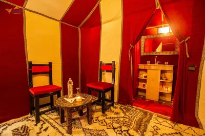 a room with two red chairs and a table at Sirocco Luxury Camp in Merzouga