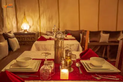 a table with a red table cloth and a bottle on it at Sirocco Luxury Camp in Merzouga
