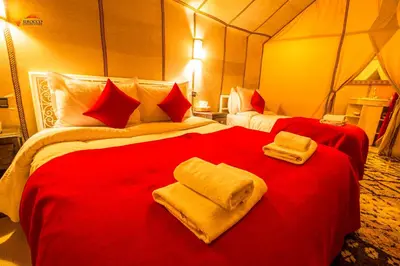 a bedroom with two red beds with towels on them at Sirocco Luxury Camp in Merzouga