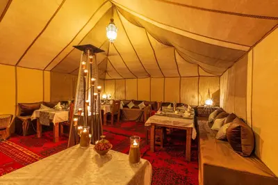 a tent with tables and couches in a room at Sirocco Luxury Camp in Merzouga