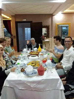 a group of people sitting around a table with food at Maison d'hôtes La Ferme AZIZA in Fès