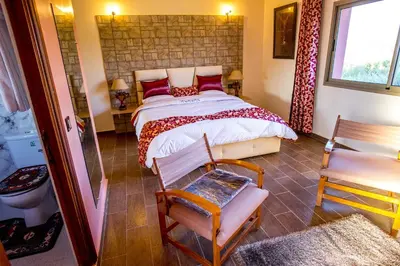 a bedroom with a large bed and a bathroom at Maison d'hôtes La Ferme AZIZA in Fès
