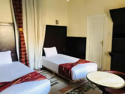 a hotel room with two beds and a table at Maison Duffal in Azrou