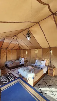 a bedroom with two beds in a tent at Desert camp camel & sandboarding in Merzouga