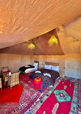 a bedroom with a bed in a room with a rug at Desert camp camel & sandboarding in Merzouga