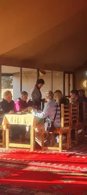 a group of people sitting at a table in a room at Desert camp camel & sandboarding in Merzouga