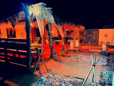 a resort with tables and umbrellas on a beach at Desert camp camel & sandboarding in Merzouga
