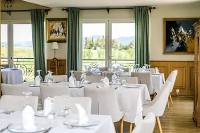 a room with white tables and chairs and windows at Le Palais des Cerisiers in Azrou