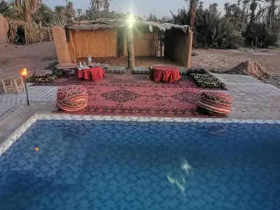 a swimming pool with a table next to a house at Camp Desert Stars in Mhamid