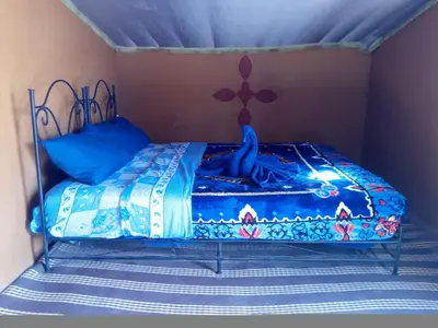 a bed with a blue comforter on it in a room at Camp Desert Stars in Mhamid