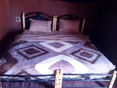 a bed with a blanket and pillows on it at Camp Desert Stars in Mhamid