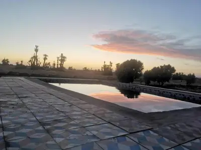 a pool of water with a sunset in the background at Camp Desert Stars in Mhamid