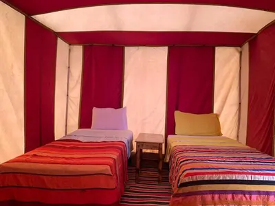 two beds in a room with red and white curtains at Camp atlantic chegaga in Mhamid