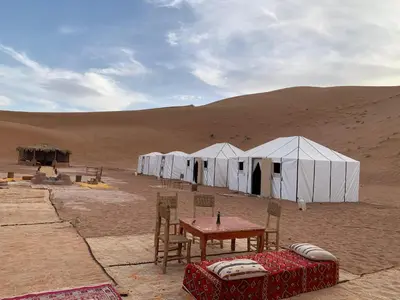 a group of white tents in the desert at Camp atlantic chegaga in Mhamid