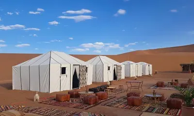 a row of white tents in the desert at Camp atlantic chegaga in Mhamid
