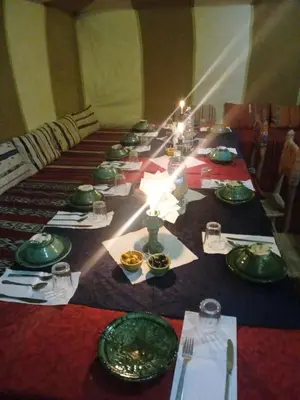 a long table with green plates and dishes on it at Camp atlantic chegaga in Mhamid