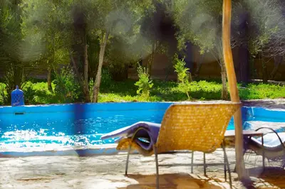 a chair and an umbrella next to a swimming pool at Dar Mouna in Aït Ben Haddou