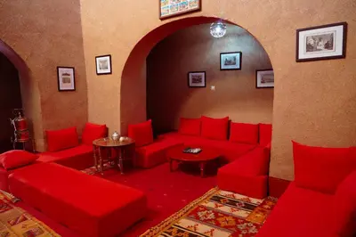 a living room with red couches and a table at Dar Mouna in Aït Ben Haddou