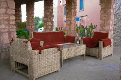 three wicker chairs and a table on a patio at Dar Mouna in Aït Ben Haddou