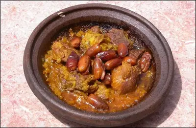 a bowl of food with beans and meat in it at Gite Elkhorbat in Tinejdad