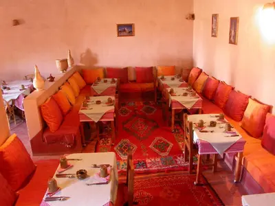 a dining room with tables and couches at Gite Elkhorbat in Tinejdad