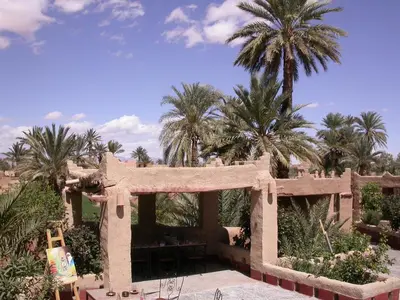 a stone building with palm trees in the background at Gite Elkhorbat in Tinejdad