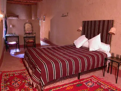 a bedroom with a large bed with a striped bedspread at Gite Elkhorbat in Tinejdad