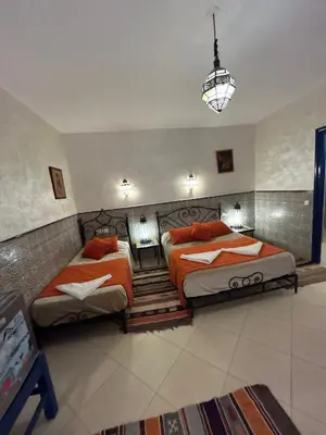 a bedroom with two beds and a chandelier at Hotel Riad Ali in Merzouga