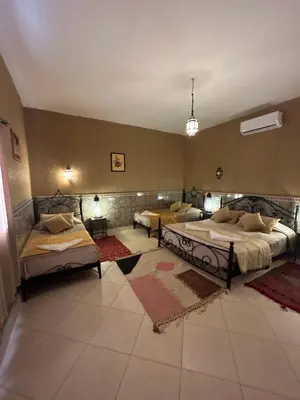 a large room with two beds and two tables at Hotel Riad Ali in Merzouga